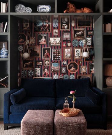 A dark blue velvet couch against a colorful wall of gallery-hung artwork