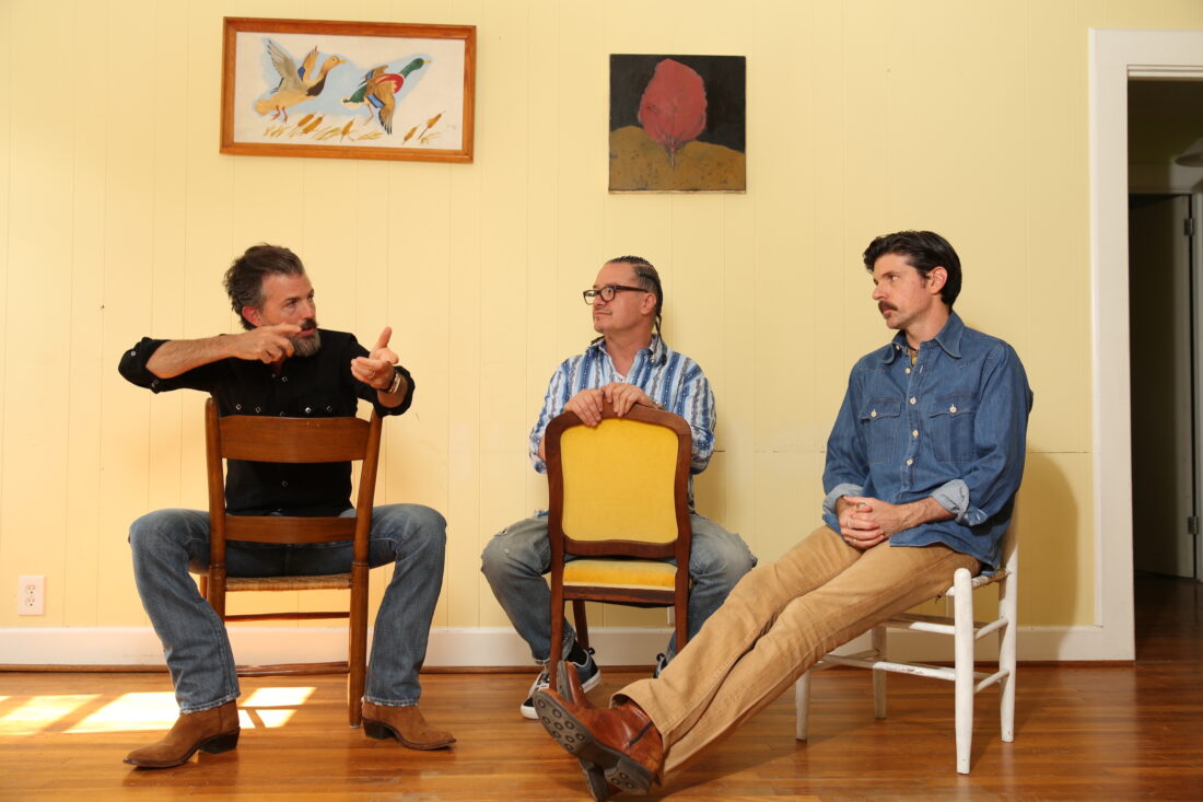 A portrait of three men in a yellow room