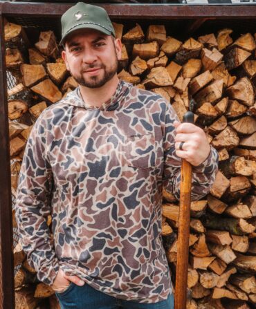 A portrait of a man in front of chopped wood