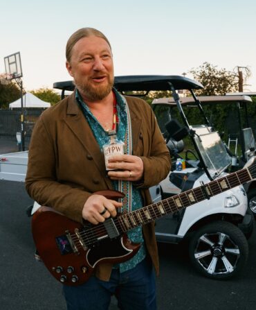Derek Trucks holds a bottle of Ass Pocket Whiskey.