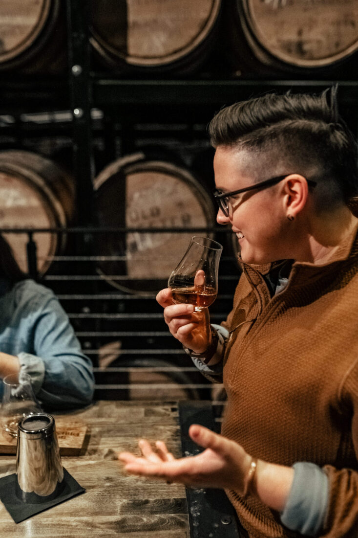 A woman sniffs a glass of bourbon