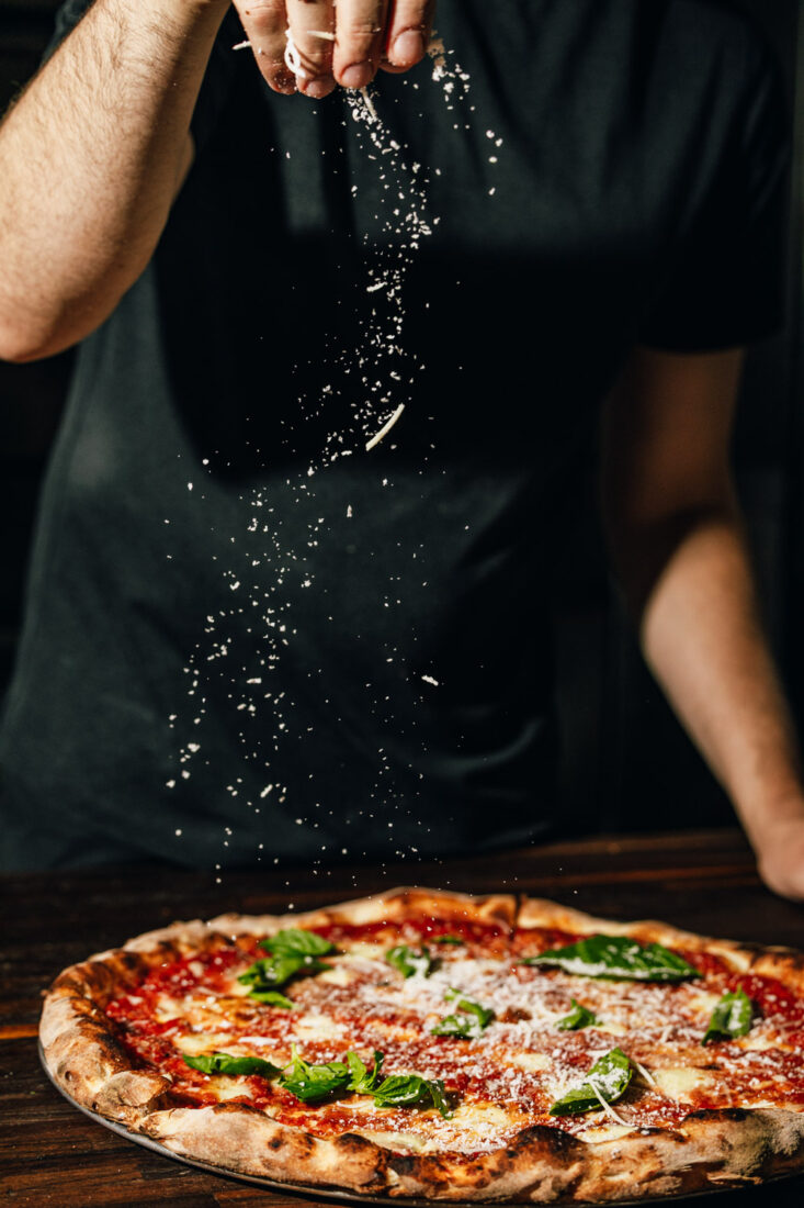 sprinkling parmesan on pizza