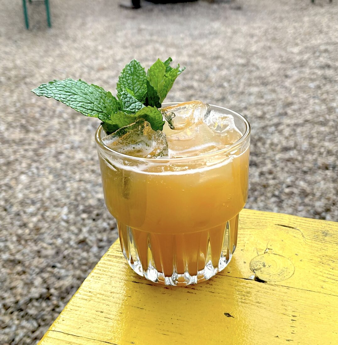 An orange cocktail in a glass with mint