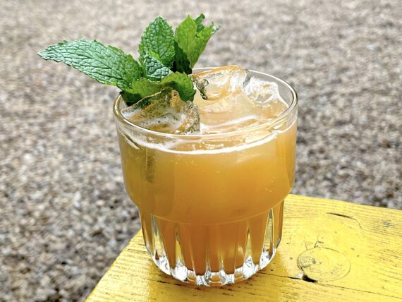 An orange cocktail in a glass with mint