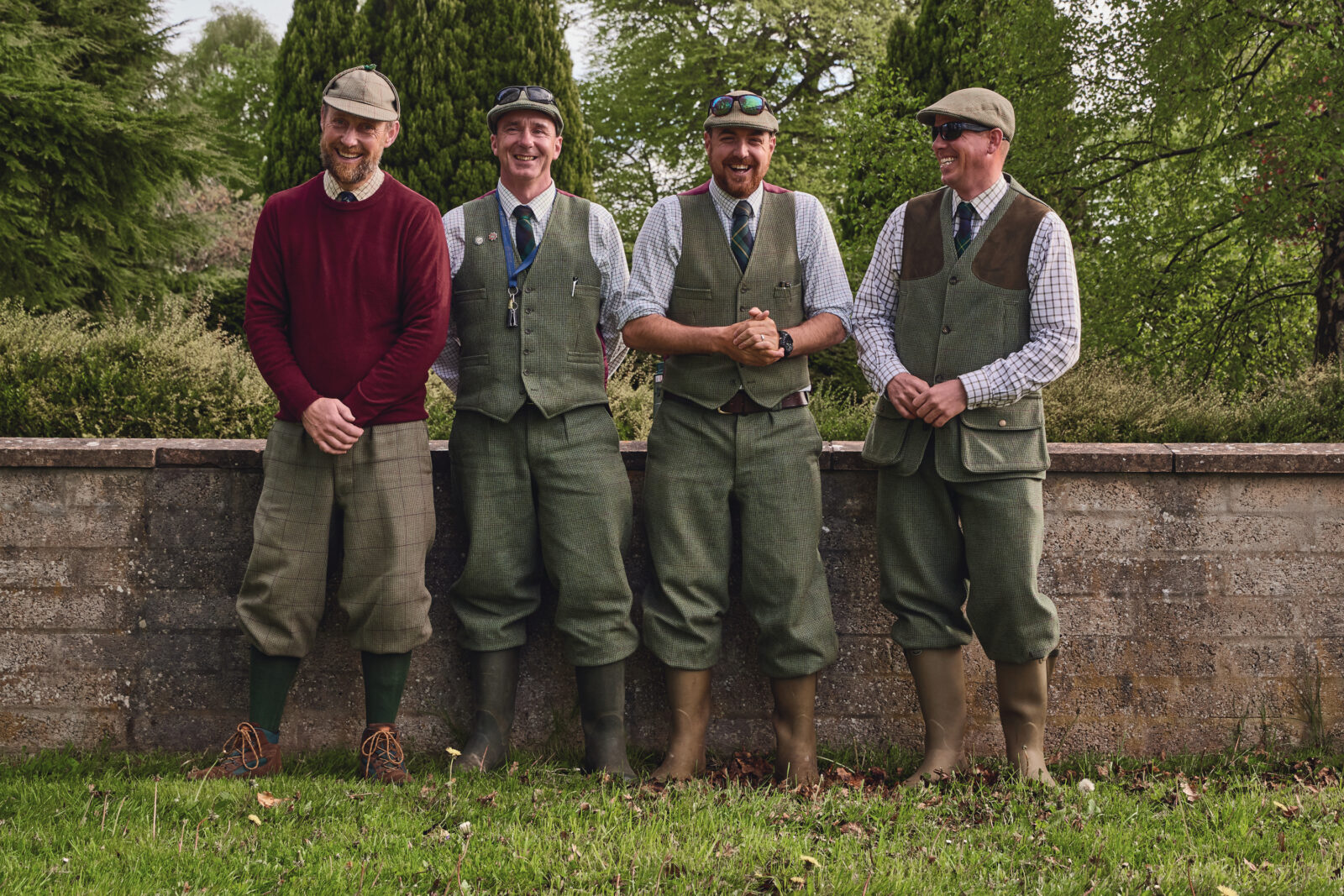 Four men in green fishing gear stand outside
