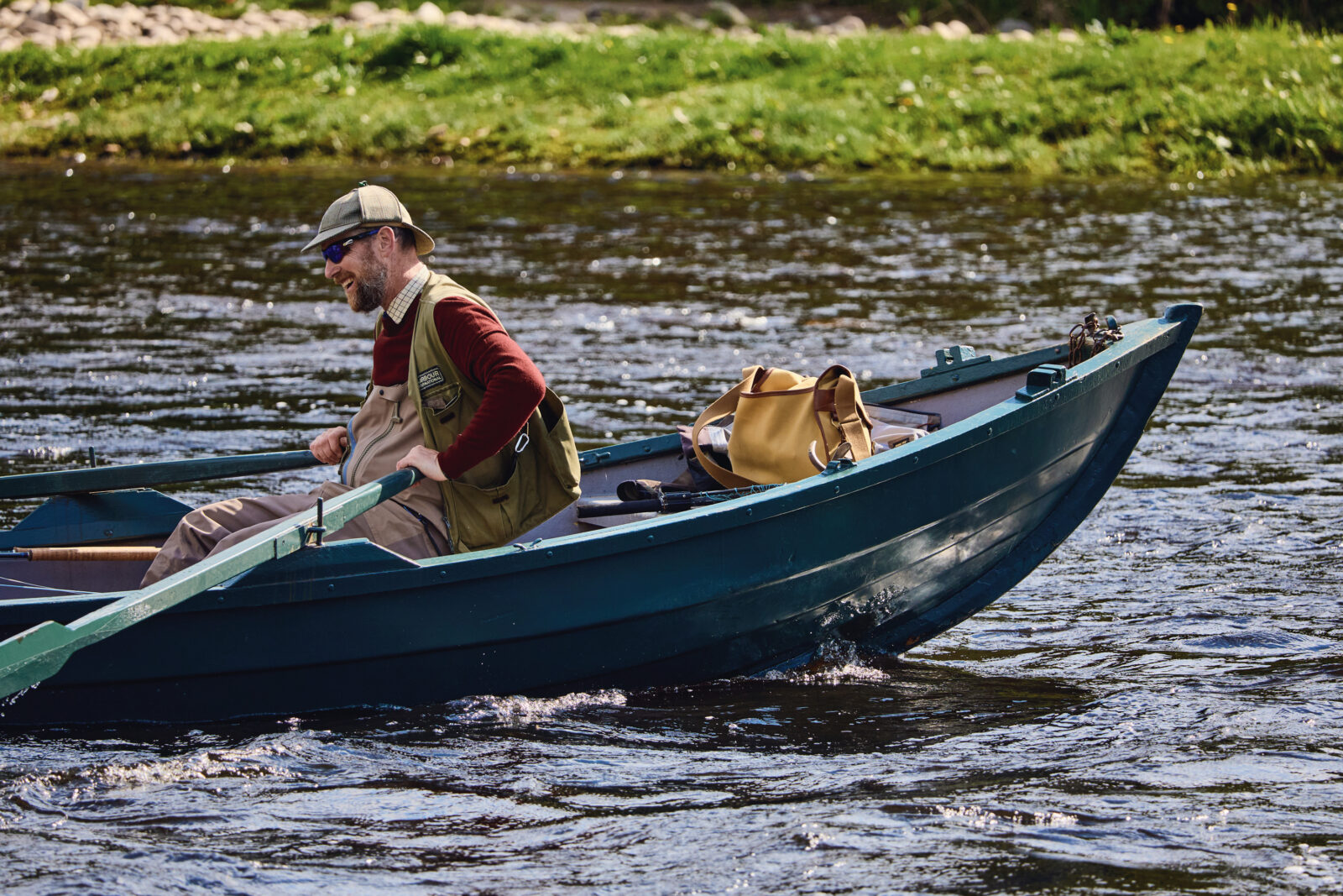 A fishing guide rows a boat in a river