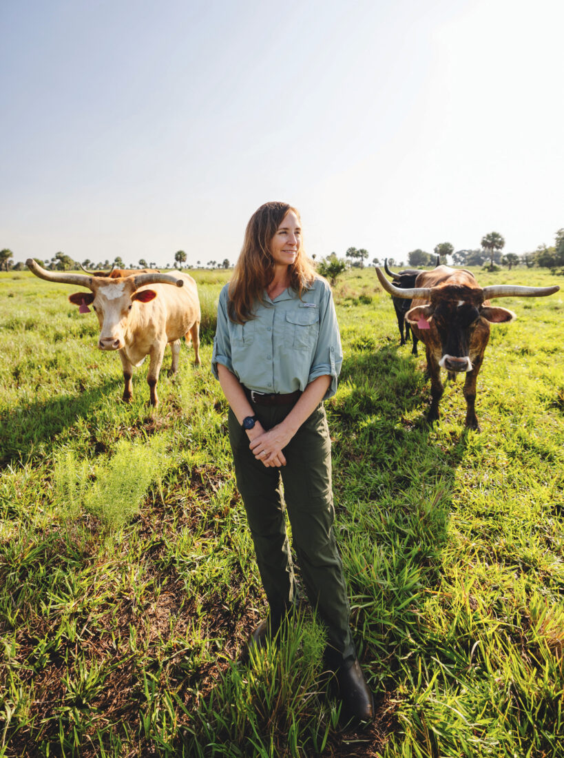 A woman stands in a field with cattle