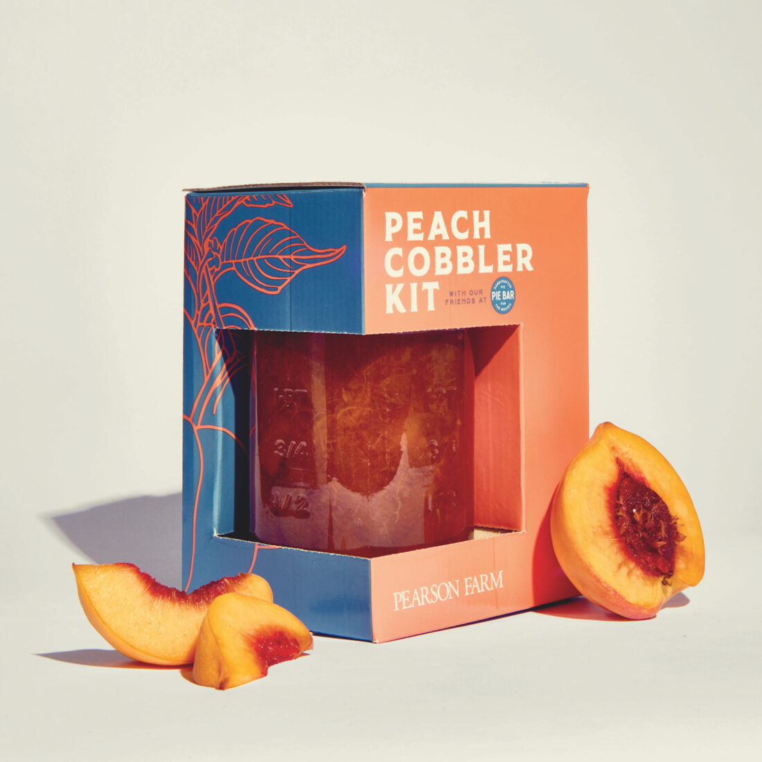 A peach cobbler kit with peaches around it
