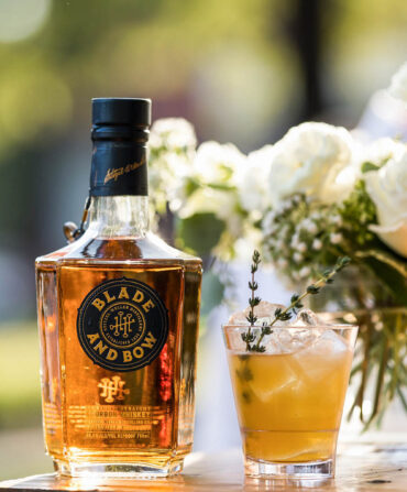 A bottle of bourbon by a cocktail